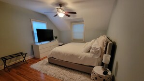 Una camera da letto con un letto, un ventilatore a soffitto, una TV e una finestra.