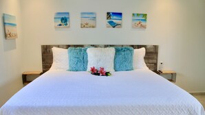 Een groot bed met een witte quilt, twee zachte kussens en een bloemdecoratie.