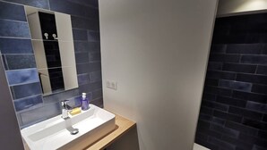 Ein modernes Badezimmer mit einem weißen Waschbecken, dunkelblauen Fliesen und einem Spiegel.