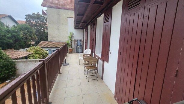 Ein Balkon mit Fliesenboden, einem Holzstuhl und einem Tisch.