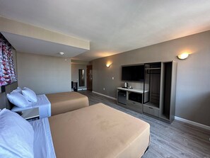 Une chambre d’hôtel avec deux lits, une télévision, un bureau avec une machine à café et une armoire.