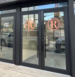 L’entrée d’un hôtel avec des portes en verre, une enseigne indiquant clairement l’adresse et le logo de l’hôtel.