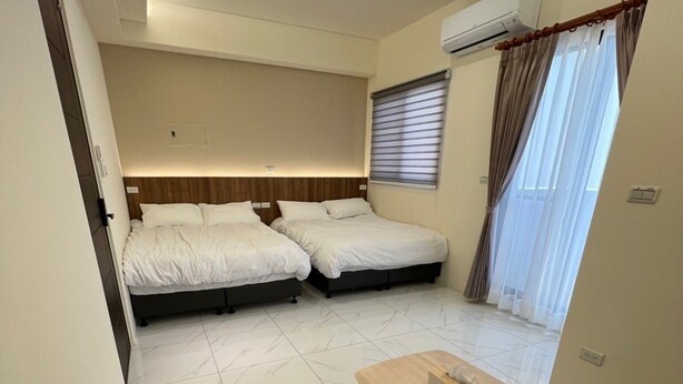Habitación de hotel con dos camas, un sofá, una mesa de madera y un equipo de aire acondicionado.