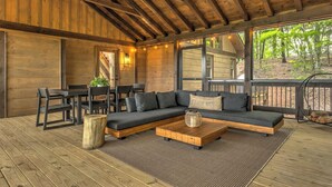 Une terrasse en bois avec un canapé modulable, des fauteuils et une table basse.