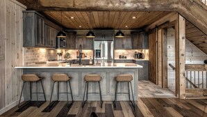 Une cuisine moderne dotée d’un grand îlot central, de tabourets de bar et d’un plafond en bois.