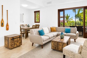 A living room with a sectional sofa, coffee table, and a dining area with a wooden table and chairs. - Walk To Beach, Grace Bay, W/Pool (#2)! (Leeward Settlement)