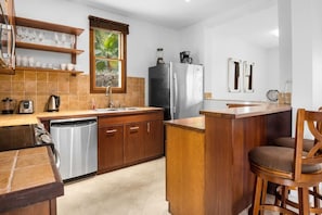 A compact kitchen with a dishwasher, a refrigerator, and a coffee maker.