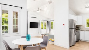 Een moderne keuken met witte kasten, een roestvrijstalen koelkast en een eethoek met een ronde tafel en stoelen.