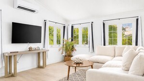 Een moderne woonkamer met een flatscreen televisie, een bank, een salontafel en een potplant.