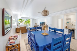 A dining area with a blue table and chairs, a hanging light fixture, and a view of the outdoors. - Stunning Yacht Club, Walk to Beach, Great Reviews! (Turtle Cove)