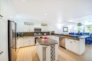 A modern kitchen with white cabinetry, granite countertops, stainless steel appliances, and a central island. - Stunning Yacht Club, Walk To Beach, Great Reviews! (Turtle Cove)
