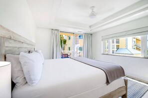 A hotel room with a large bed, a window with a view of buildings, and a balcony. - Stunning Yacht Club, Walk To Beach, Great Reviews! (Turtle Cove)