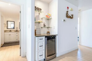 Una cocina moderna con armarios blancos, lavavajillas integrado y una estantería de vidrio con objetos decorativos.