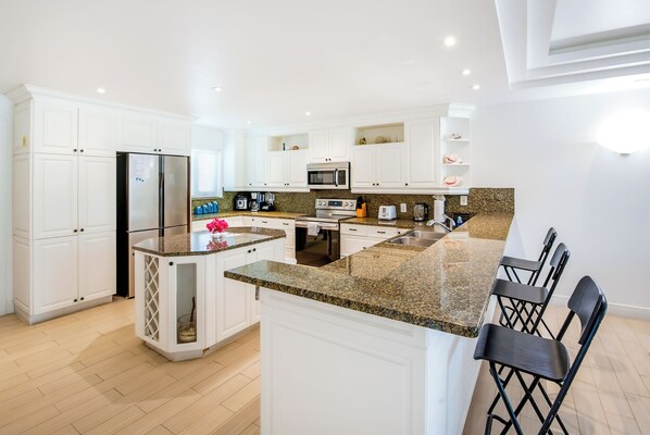 A modern kitchen with white cabinetry, a granite countertop, and a built-in oven.