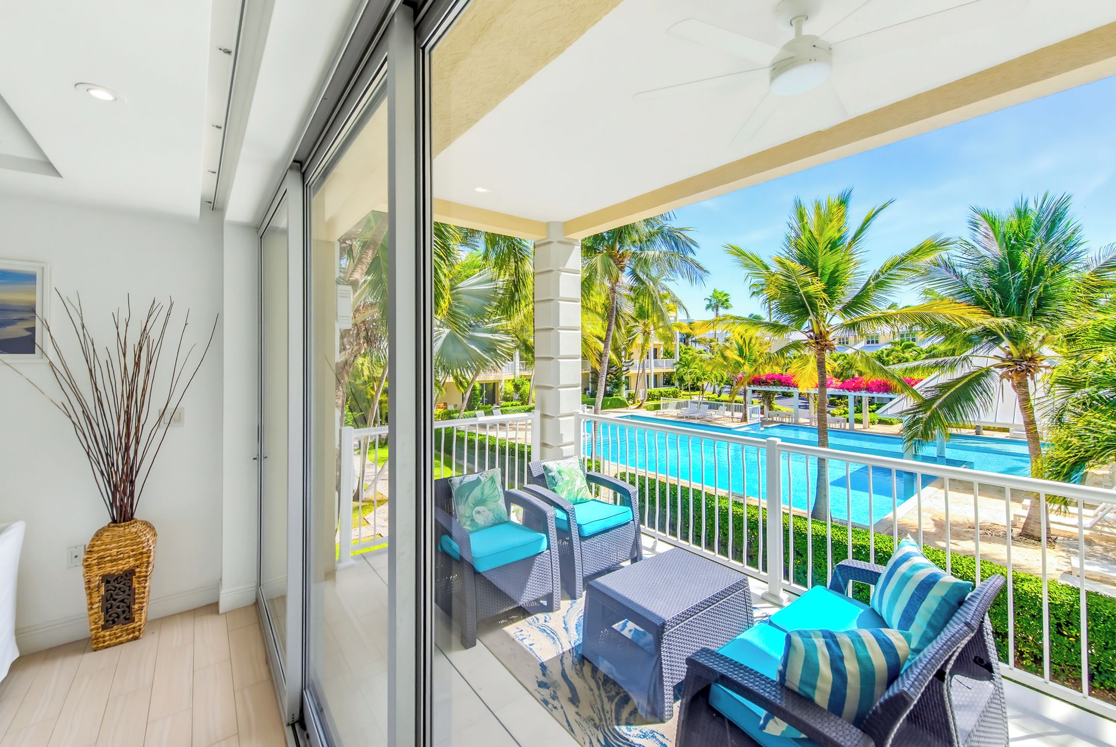 A balcony with a view of a swimming pool, outdoor furniture, and a decorative vase.