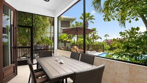 Un patio con mesa y sillas, una piscina y vistas a una casa y follaje.