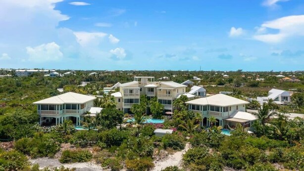 Une propriété située sur la côte, comprenant plusieurs bâtiments, une piscine et une végétation luxuriante.