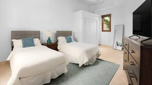 Habitación de hotel con dos camas, una cómoda, un televisor y una ventana con vistas a palmeras.