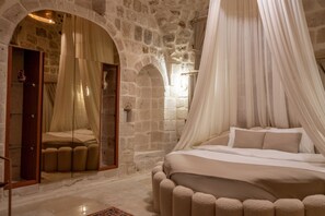 A bedroom with a stone wall, a bed with a canopy, and a mirror. - Ana Talia House  (Mardin)
