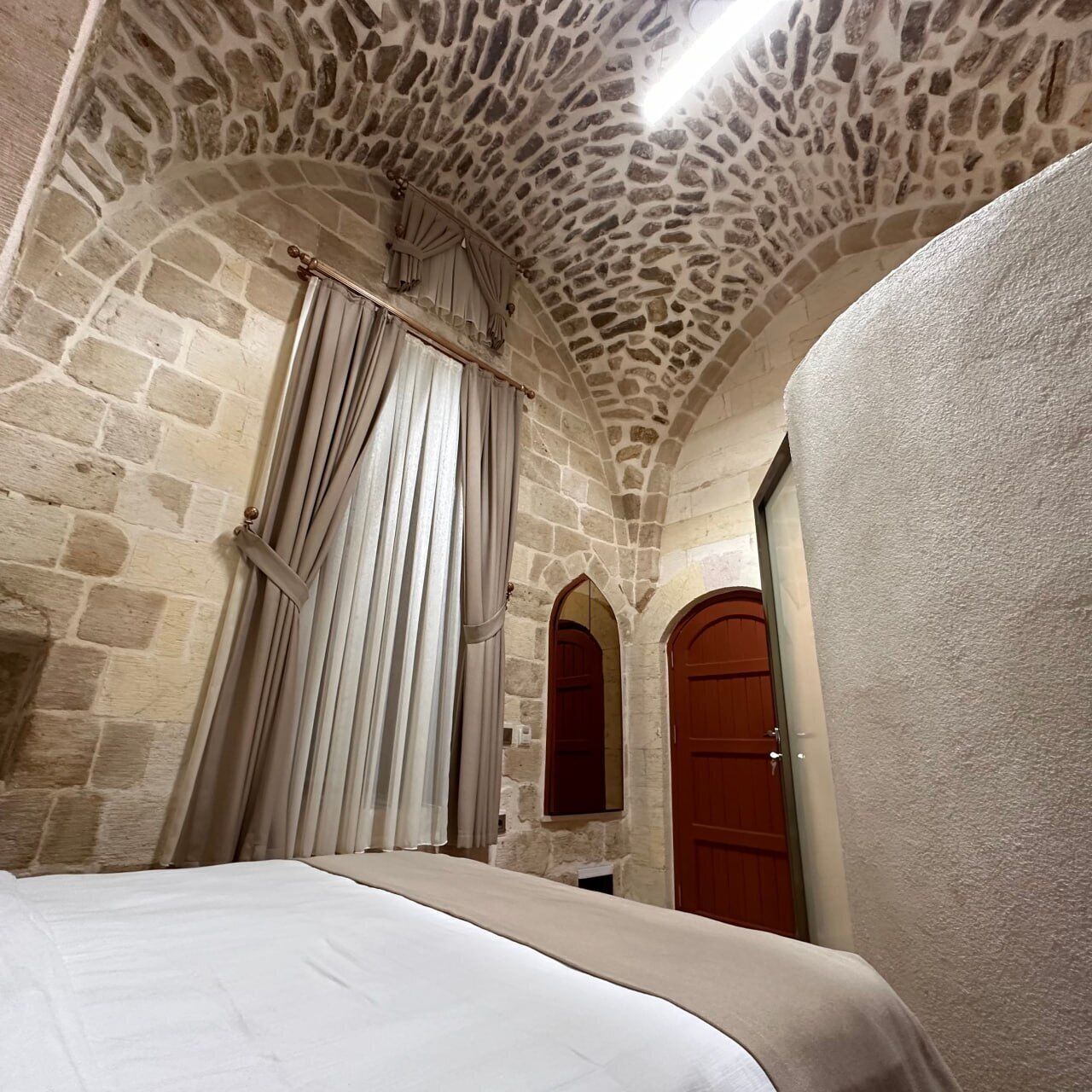 Una habitación con techo de piedra, una cama y dos puertas de madera.