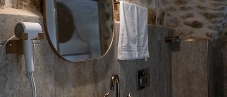 Un baño de piedra con un lavabo redondo, un espejo y una toalla colgada en la pared.