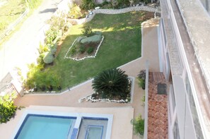 Un jardín en la azotea con piscina, sendero de piedra y diferentes plantas.