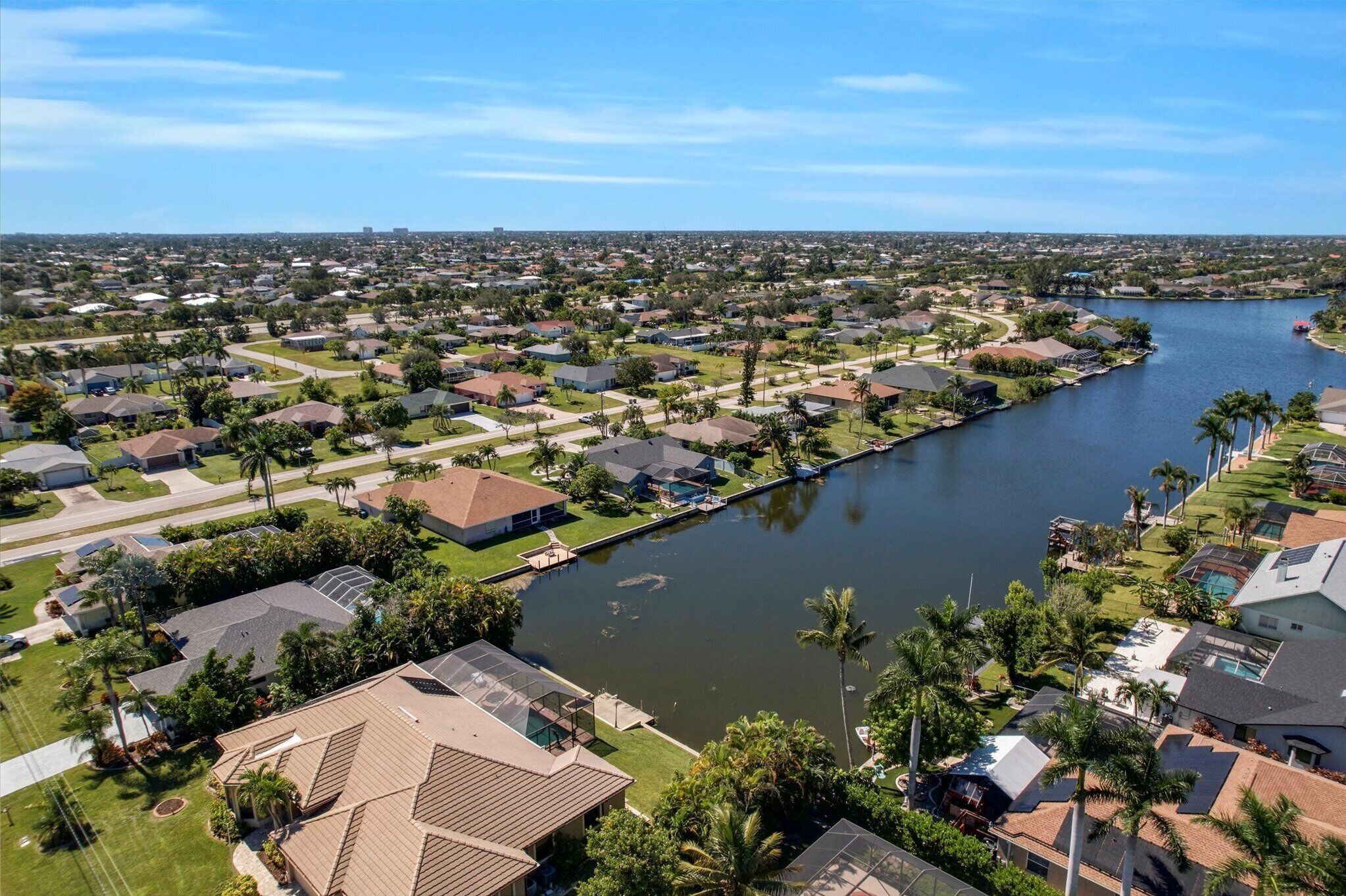 An aerial view of a residential area with houses, a river, and a bridge.