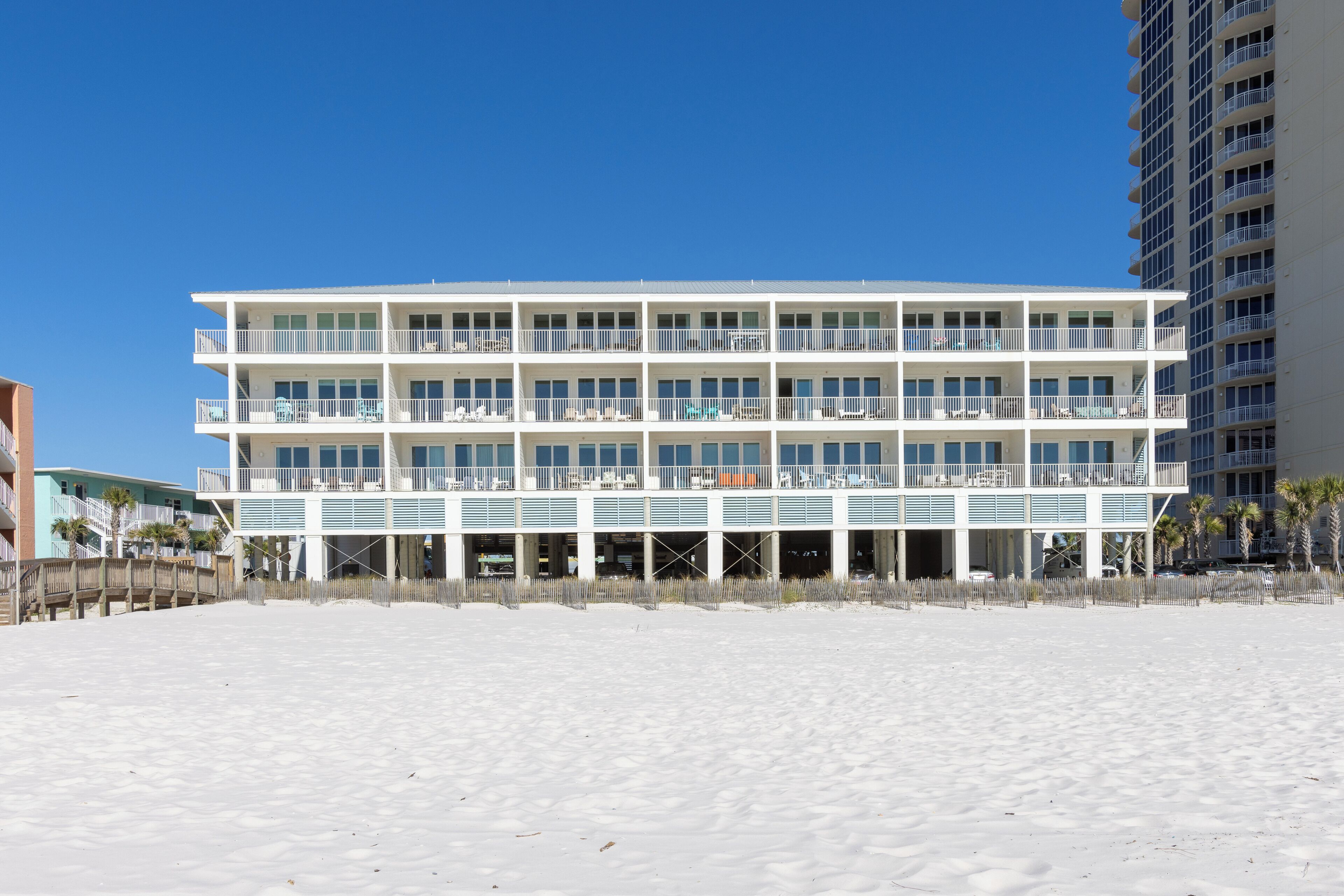 A multi-story hotel with balconies, a beach view, and a parking garage.