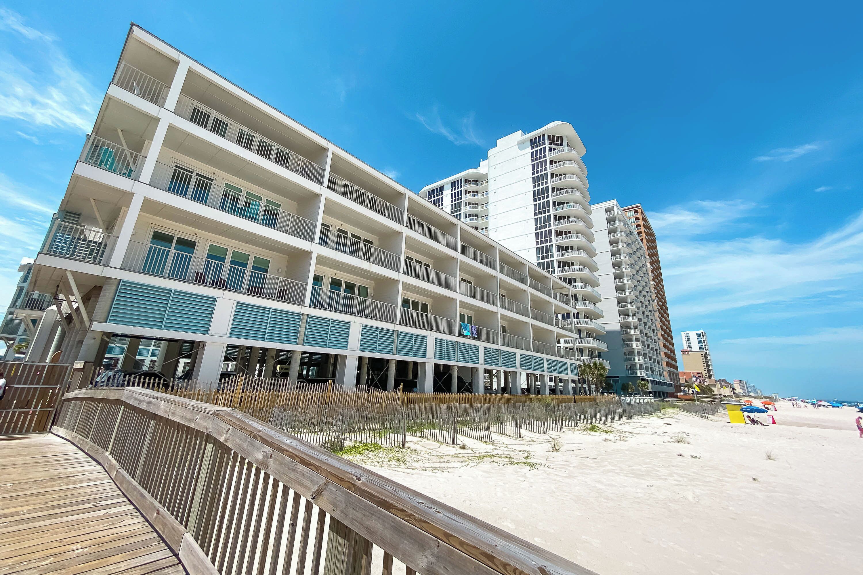 A multi-story hotel with balconies and a beach view.