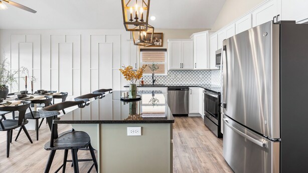 A modern kitchen with a central island, stainless steel appliances, and a pendant light fixture.