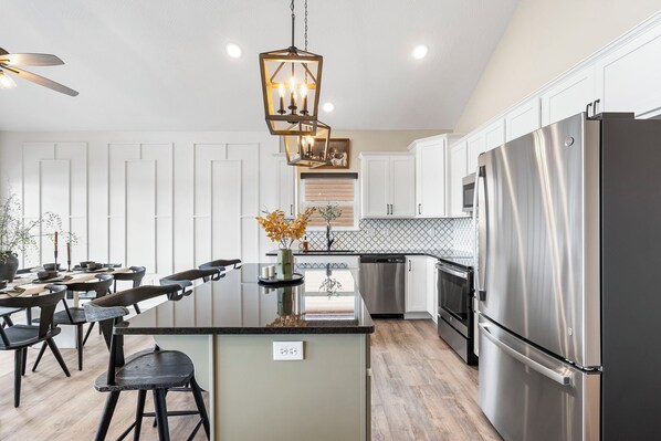 A modern kitchen with a central island, stainless steel appliances, and a pendant light fixture.