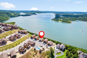 An aerial view of a lakeside resort with multiple buildings, a swimming pool, and boats on the water.