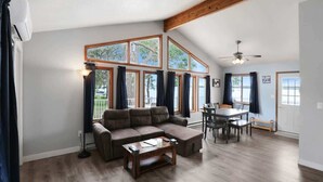 A spacious living area with a large sectional sofa, a dining table, and multiple windows. - Amazing Grace Etta Shores (Henning)