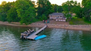 A dock extending into a body of water with a house and outdoor seating area in the background. - Amazing Grace Etta Shores (Henning)