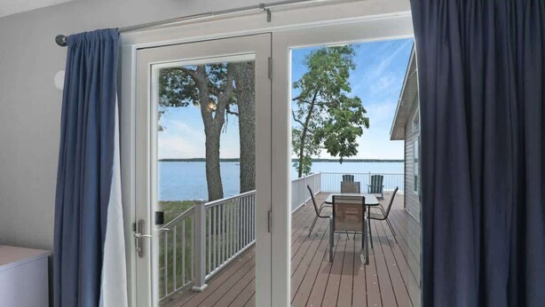 A deck with a table and chairs, a railing, and a view of the water. - Amazing Grace Etta Shores (Henning)