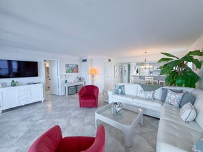 Un salon moderne avec un téléviseur à écran plat, des meubles rouges et blancs, et une grande plante.