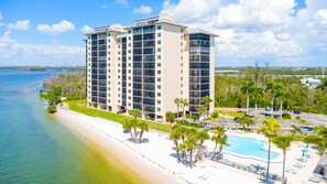 Un grand hôtel avec de nombreux étages, situé en bord de mer et doté d’une piscine.