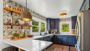 Une cuisine moderne dotée d’un îlot central, de meubles de rangement aux couleurs sombres et d’un grand réfrigérateur.