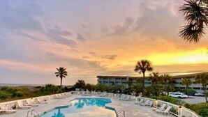A pool area with lounge chairs and a view of the ocean at sunset. - 3rd Floor Condo w/Amazing Ocean Views! Pool & Pier Access! In Heart of IOP! *Unit 321* (Isle Of Palms)