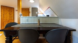 Un comedor con mesa y sillas, una cocina al fondo y una puerta de madera.