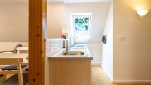 Eine kleine Küche mit Fenster, Spüle und Essbereich mit Stühlen.