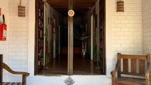 A corridor with a sign reading "SAIDA" at the entrance, leading to a room with a wooden bench and a fire extinguisher on the wall. - Pico da Tribo Pousada (Imbituba)