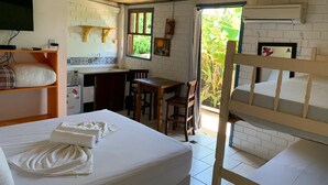 A room with a bed, a desk, and a bunk bed. There is a window with a view of greenery outside. - Pico da Tribo Pousada (Imbituba)