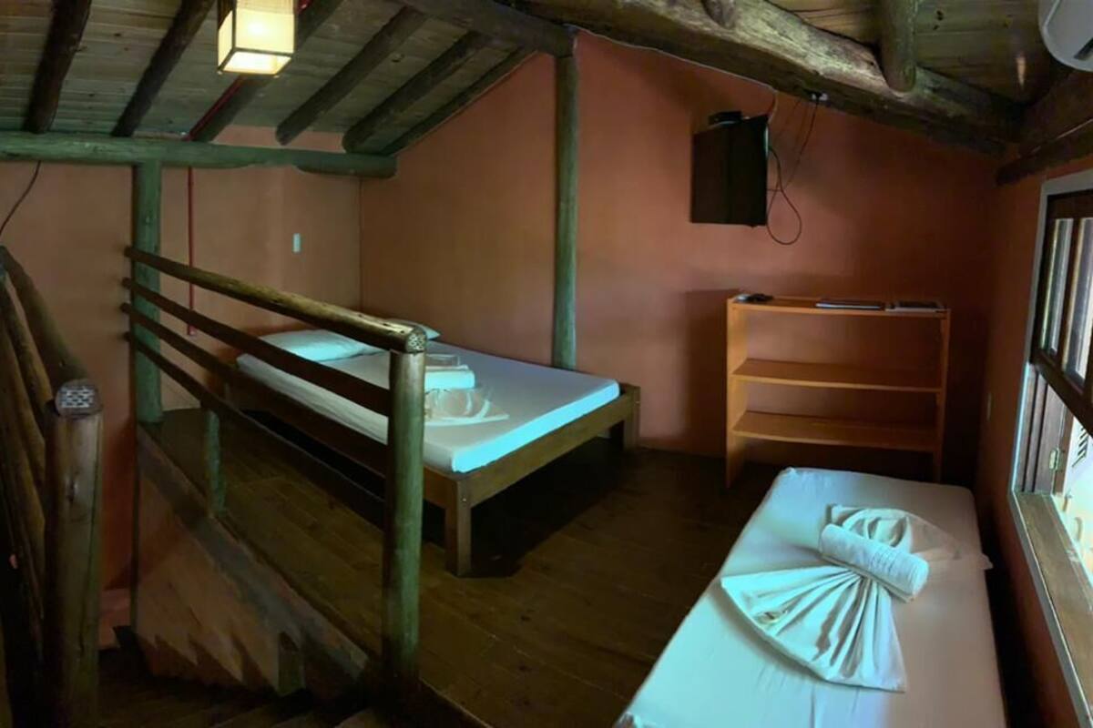 Une chambre rustique avec deux lits superposés, une étagère en bois et une fenêtre.