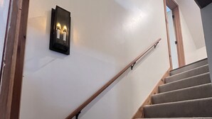 Eine Treppe mit Teppichstufen und Holzhandläufen, die zu einer Tür am Obergeschoss führt.