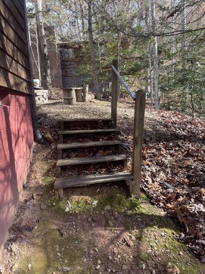 A wooden staircase leading to a cabin in a forested area.
