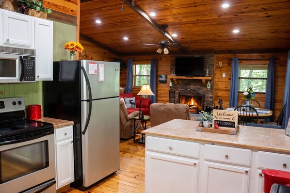A cozy cabin interior with a kitchen, dining area, and fireplace.