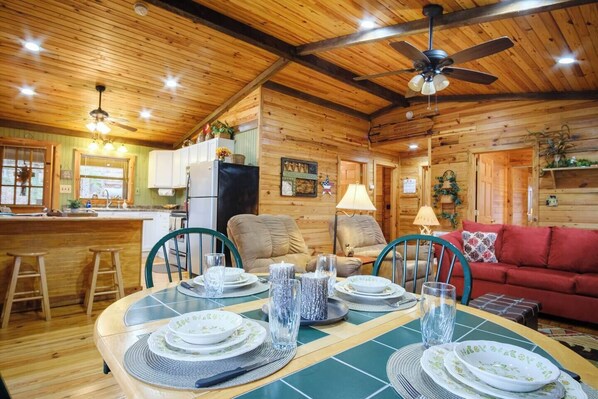 Un interior de cabaña acogedor con comedor, cocina y sala de estar.
