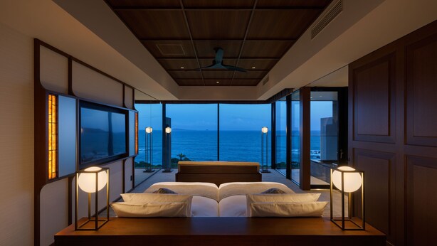 A bedroom with a large bed, bedside lamps, and a view of the ocean. - GOTO RETREAT by Onko Chishin (Goto)