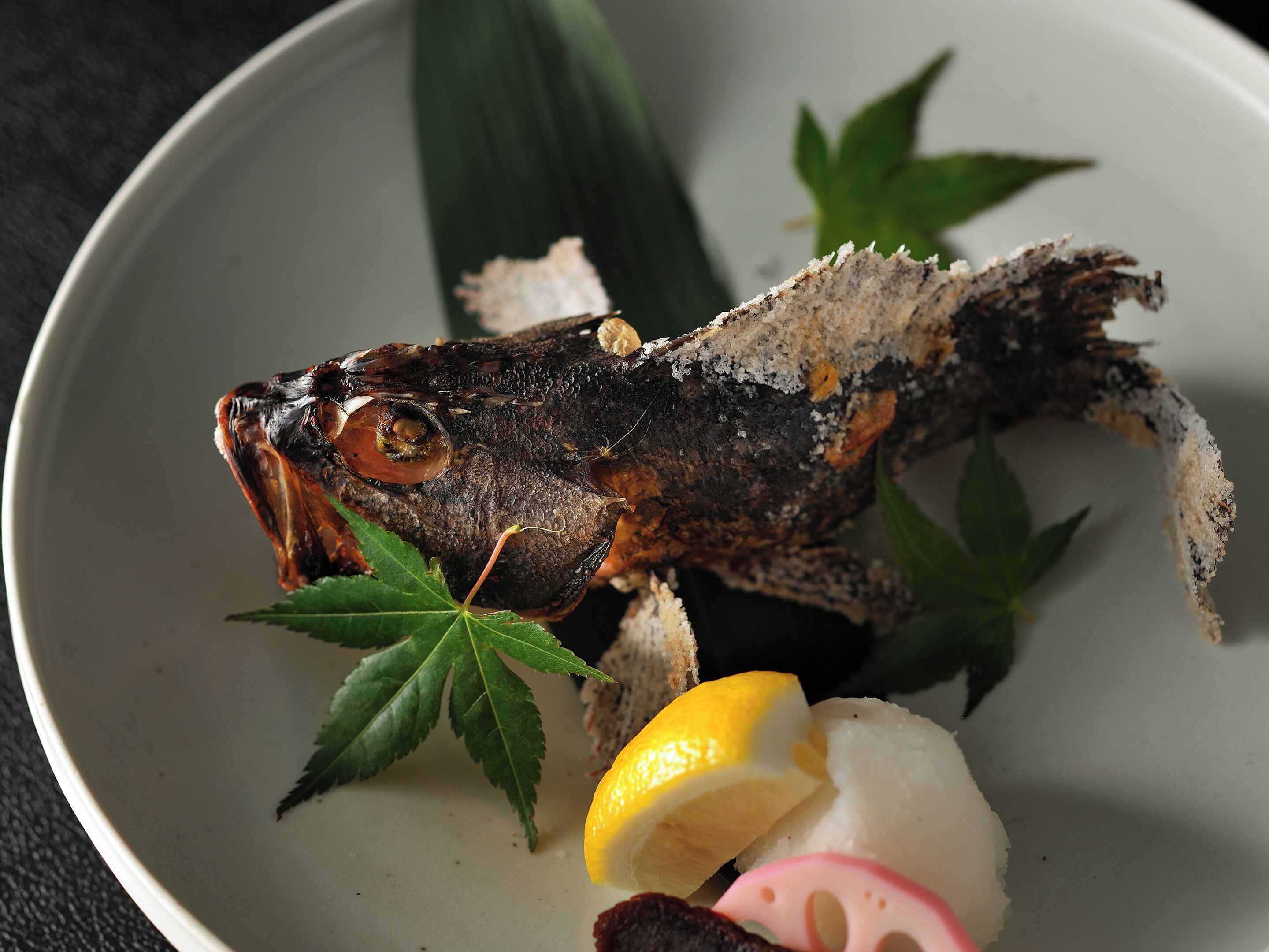 A fish dish with lemon and radish on a plate.